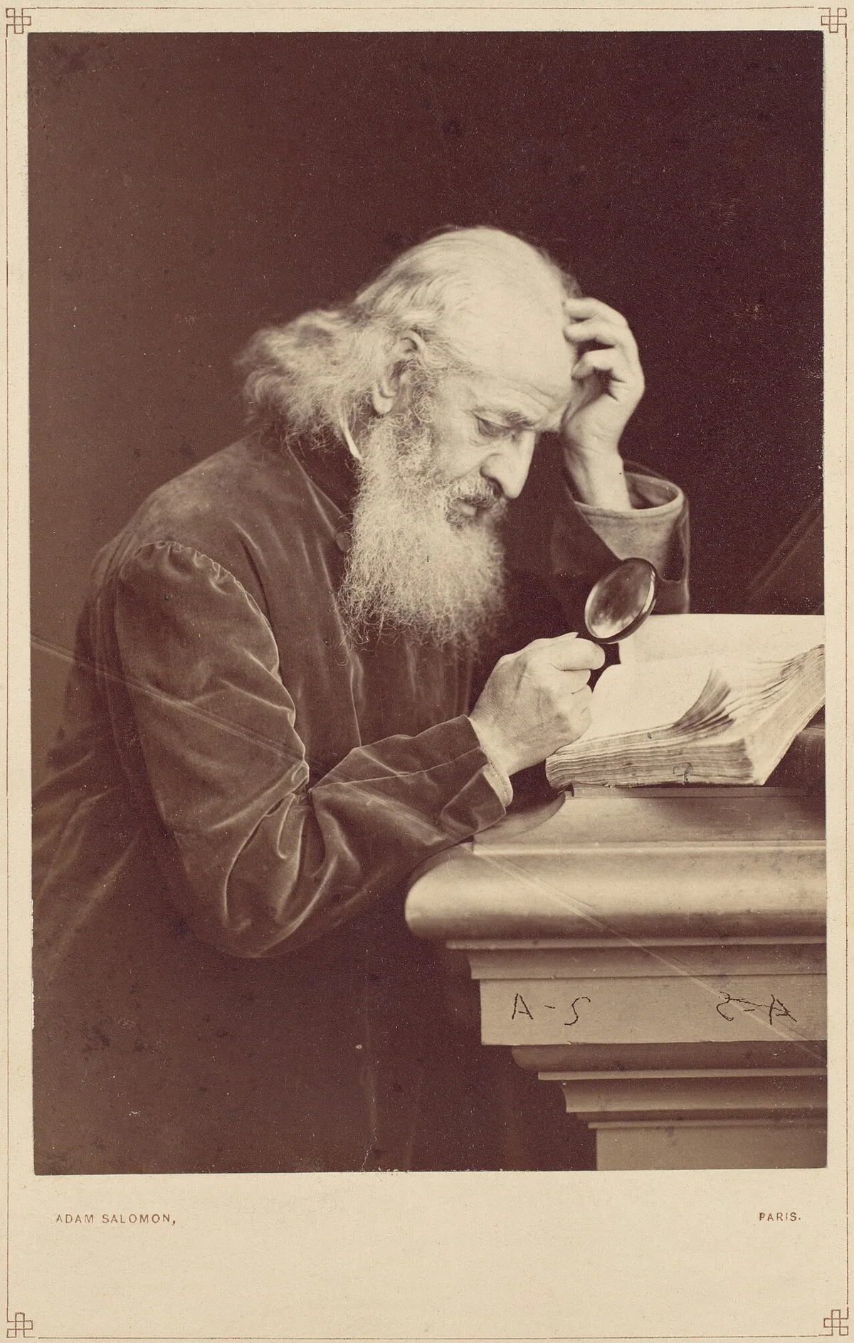 Een oudere man met baard in een fluwelen jas bestudeert een opengeslagen boek door een vergrootglas, historische fotografie.